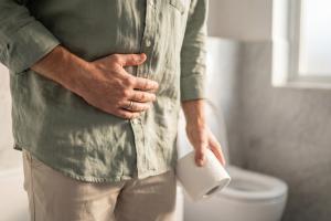 Constipated man holding his stomach in a bathroom