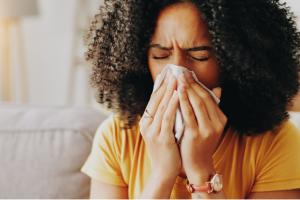 Woman blowing her nose into a tissue while experiencing sinus congestion