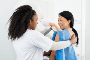 Happy Woman Looking At Doctor While Undergoing Mammogram X-ray