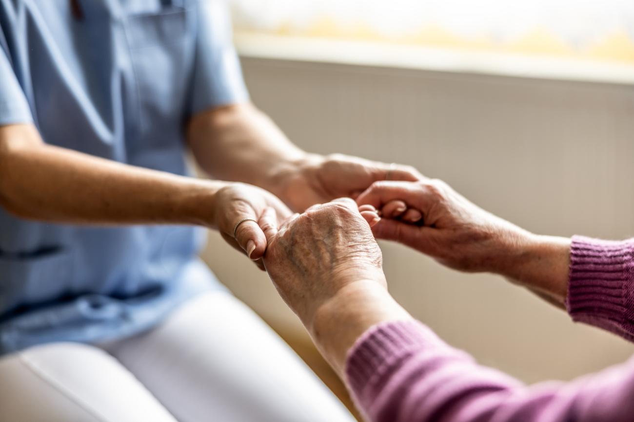 healthcare worker holding elderly patient's hand