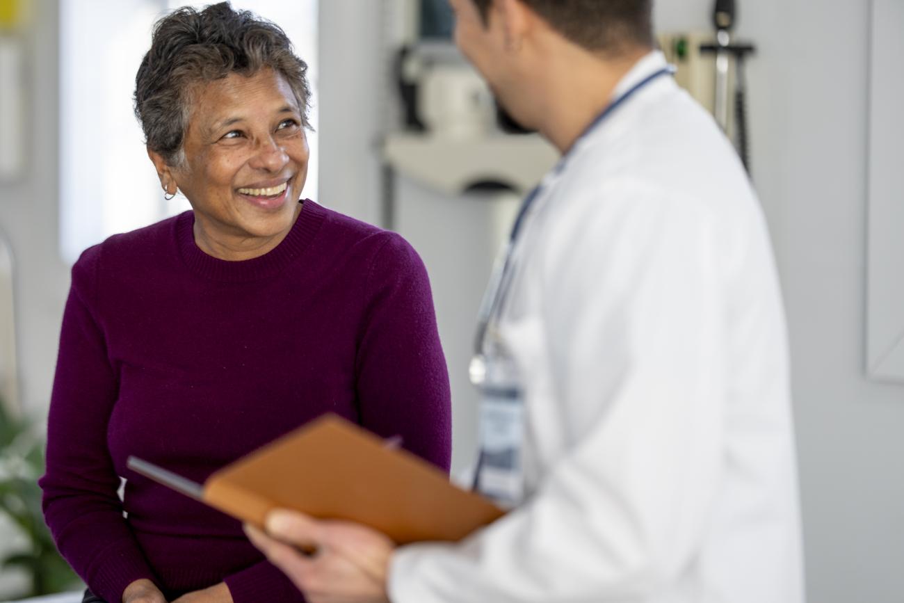 Smiling senior female patient talks with a doctor during a friendly medical consultation in a bright clinic