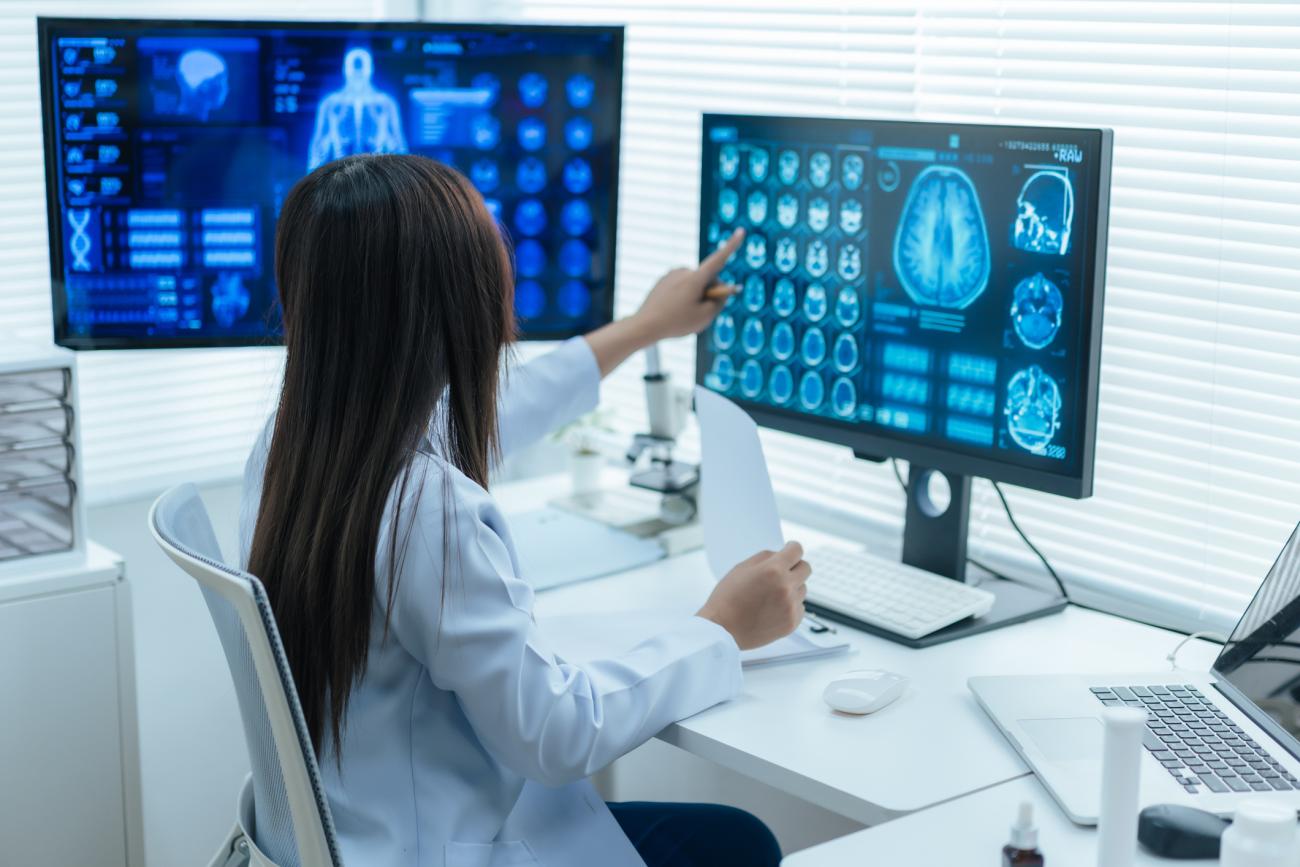 Woman doctor examines human brain medical scan on computer monitor in hospital laboratory
