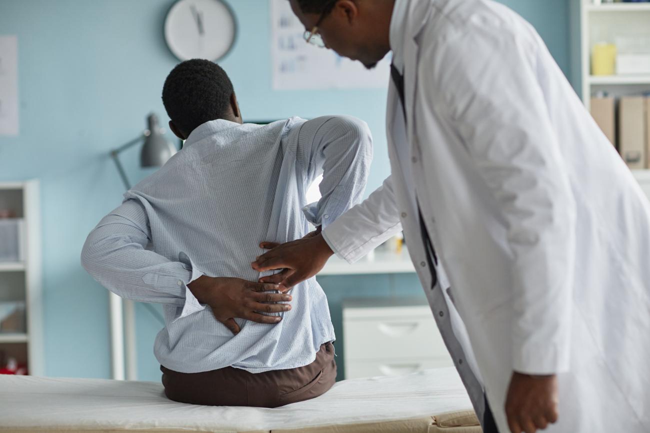  Young Adult Black Man Experiencing Back Pain during Medical Examination