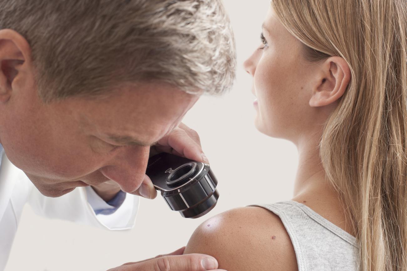 Doctor examining mole on woman's shoulder